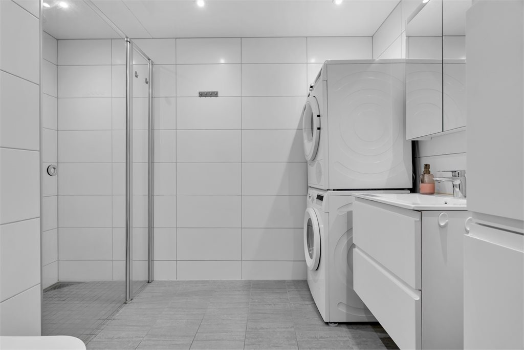 Flislagt bad med opplegg for vaskemaskin og tørketrommel.