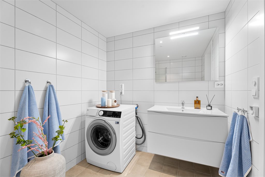 Romslig bad med innredning, stort speil og opplegg for vaskemaskin.